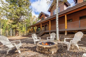 A lodge with a fire pit and Adirondack chairs in the outdoor seating area.
