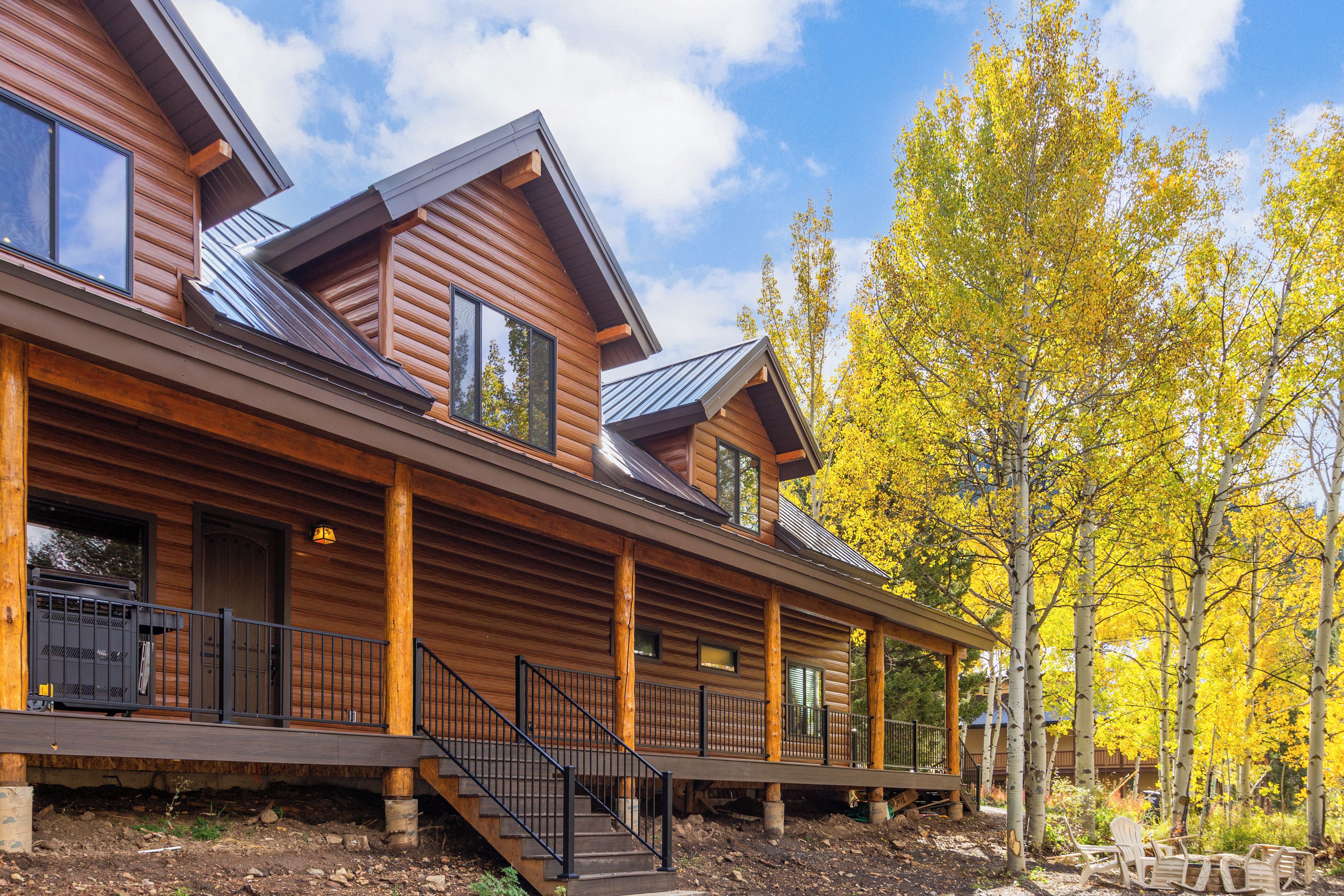 A log cabin with a covered porch, multiple windows, and a staircase leading to the upper level.