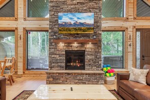 A stone fireplace with a framed picture above it, a wooden bench, and a couch with colorful towels.