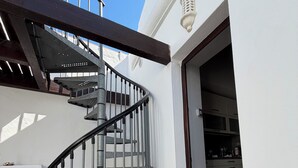 A spiral staircase with metal railings leading to a white-walled interior.