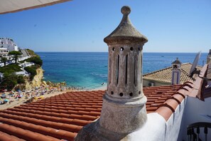 Ein Küstengebäude mit Ziegeldach mit Blick auf einen Strand und das Meer.