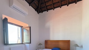 A bedroom with a wooden bed, a window, a radiator, and a tiled floor.