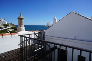 A balcony with a metal railing overlooking a coastal view, including a lighthouse and a sailboat on the water. - A House by the Atlantic Ocean in Carvoeiro (Carvoeiro)