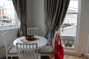 A room with a round table, white chairs, a bowl of fruit, and a red bag. - Mezzanine studio flat in the heart of Notting Hill (London)