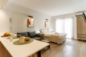 A modern hotel room with a sofa, a bed, a dining area with a table, and a large window with curtains. - Hestia Stays at Fitz Roy 1900 (Buenos Aires)