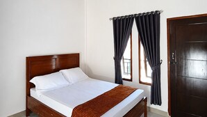 A bedroom with a wooden bed, white bedding, a brown throw blanket, a window with curtains, and a dark door. - Waetuak Homestay (Manggarai barat)