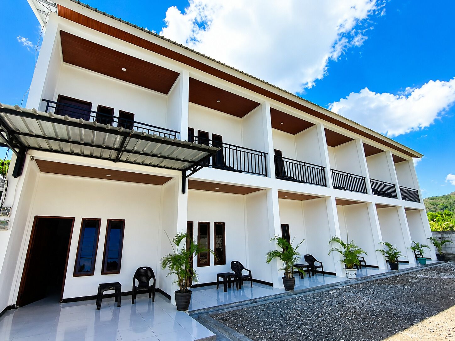A multi-story hotel with balconies, outdoor seating, and potted plants.