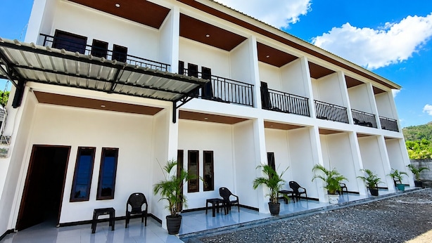 A multi-story hotel with balconies, outdoor seating, and potted plants. - Waetuak Homestay (Manggarai barat)