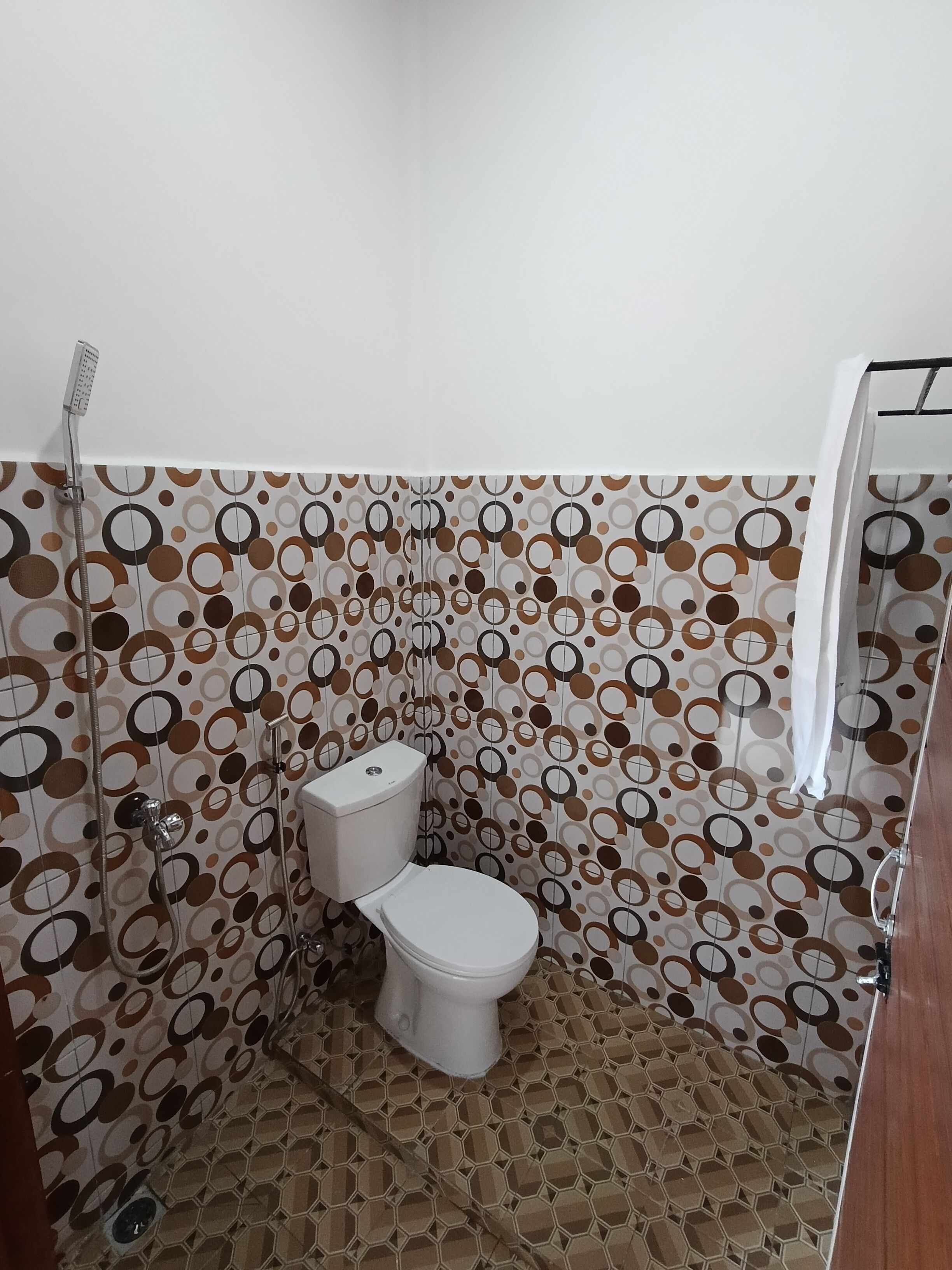 A bathroom with a toilet, shower, and a patterned wall.