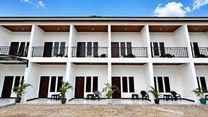 A multi-story building with balconies, doors, and potted plants. - Waetuak Homestay (Manggarai barat)