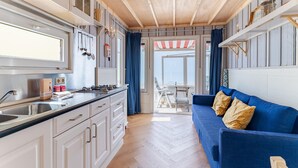 Cocina compacta con lavaplatos, estufa y alacenas, que da a un balcón con vistas.