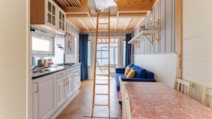Una cocina moderna con armarios blancos, techo de madera y una escalera de madera central.
