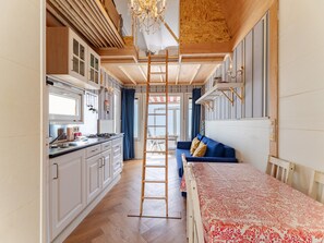 Una cocina moderna con armarios blancos, techo de madera y una escalera de madera central.