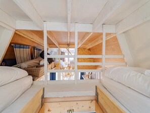Un dormitorio estilo loft con dos camas, techo de madera y vistas al exterior.