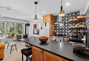 A modern kitchen with a large island, wooden cabinets, and a black and white patterned backsplash. - Elk Park 1 bedroom retreat (Columbia Falls)