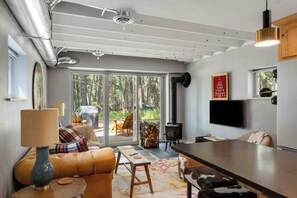 A modern living room with a sofa, a coffee table, a fireplace, and a television. - Elk Park 1 bedroom retreat (Columbia Falls)