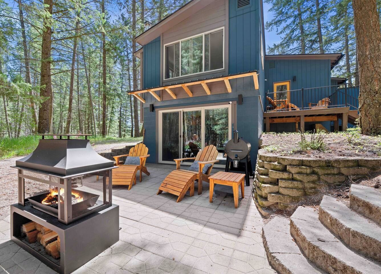 A modern outdoor deck with a fire pit, lounge chairs, and a grill area.