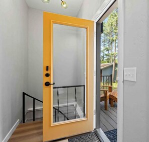 Eine Tür mit Glasfenster, einem schwarzen Metallgeländer und einer Holztreppe, die zu einer Außenterrasse führt.