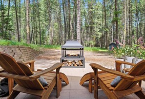 Eine Terrasse mit zwei Holzstühlen und einem Steinkamin.