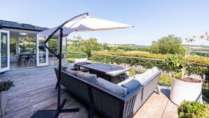 Eine Terrasse im Freien mit Essbereich, einer Couch und einem großen Sonnenschirm.
