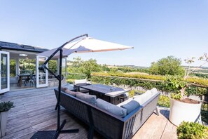 En udendørs terrasse med spiseplads, en sofa og en stor parasol.