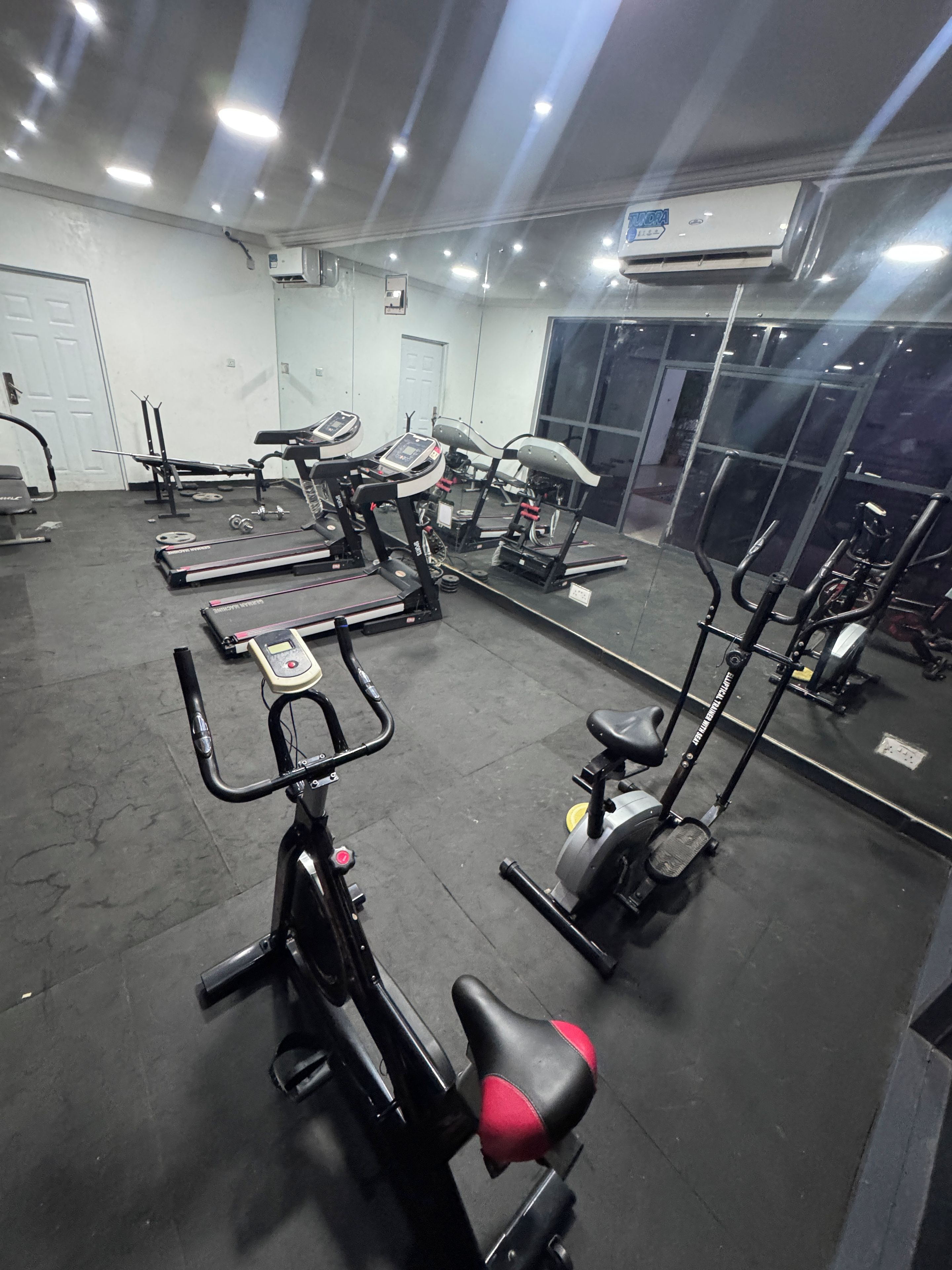 A gym with various exercise equipment including treadmills, stationary bikes, and weight machines.