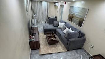 A modern living room with a grey sectional sofa, a coffee table, and a rug.