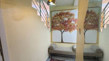 A hallway with a staircase, a bench, and a patterned rug.