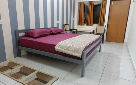 A bedroom with a bed, a chair, a desk, and a wardrobe.