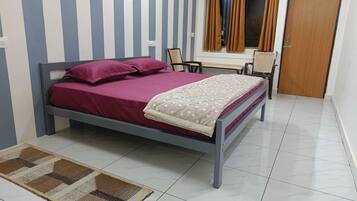 Un dormitorio con cama, una silla, un escritorio y un armario.