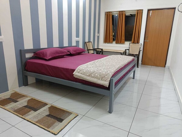 A bedroom with a bed, a chair, a desk, and a wardrobe.