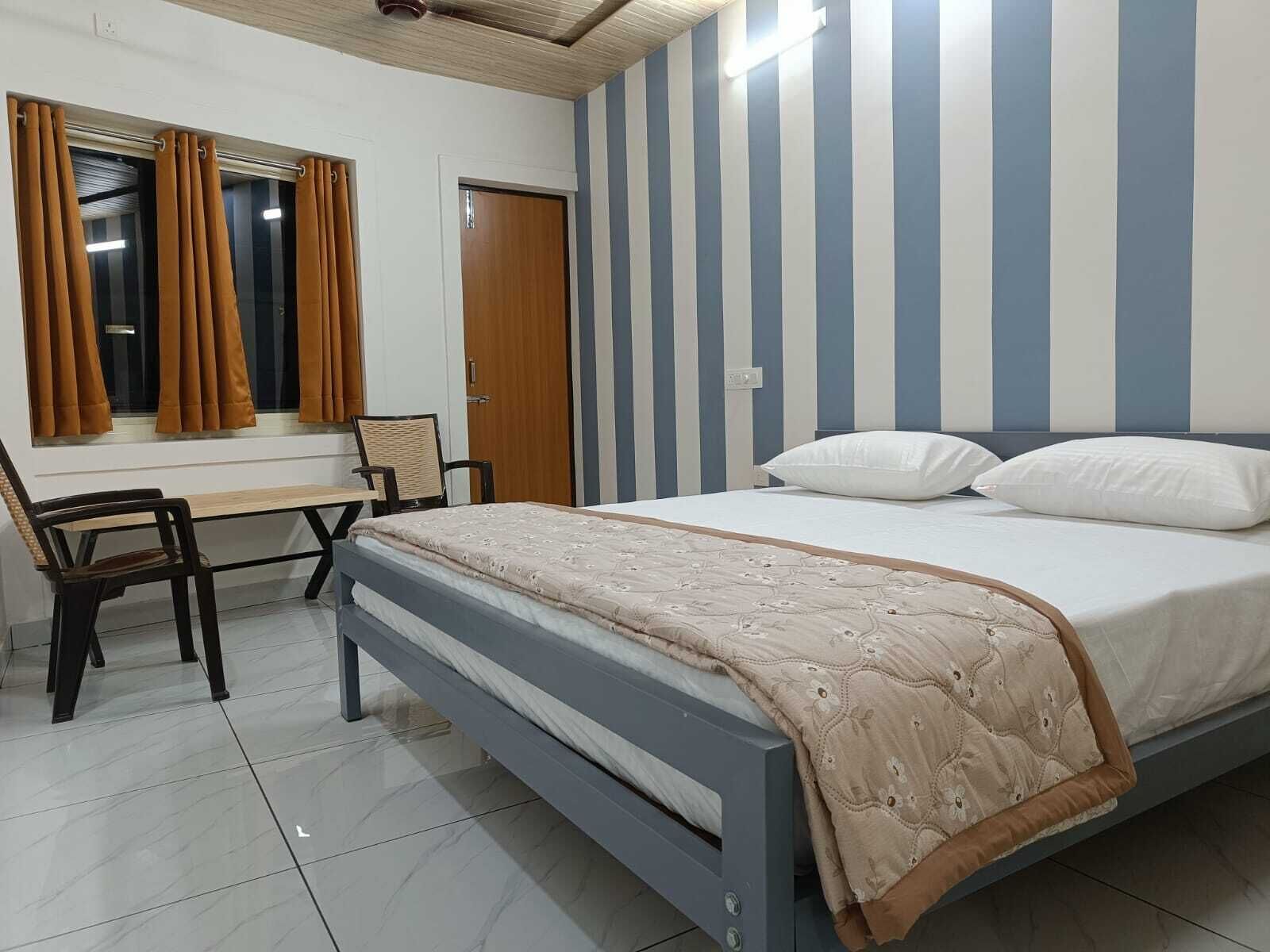 A bedroom with a bed, a desk, and a chair.