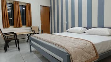 A bedroom with a bed, a desk, and a chair.