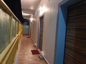 Un pasillo con suelo de baldosas, puertas a la derecha y una ventana a la izquierda.