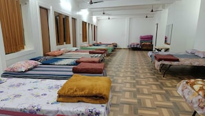 A dormitory room with multiple beds, each with a different patterned bedspread and a variety of pillows. - Hotel Deewan Saray (Haldwani)