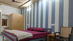 A bedroom with a bed, a wardrobe, a chair, and a mirror. - Hotel Deewan Saray (Haldwani)