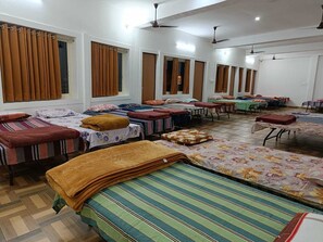 A hotel room with multiple beds, each with a different colored bedspread, and a large window with curtains.