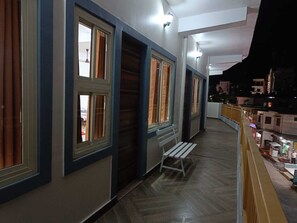 A corridor with multiple windows, a bench, and a railing.