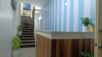 Un área de recepción con pared a rayas, un mostrador de madera y una escalera que lleva a un piso superior.
