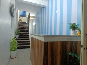 A reception area with a striped wall, a wooden reception desk, and a staircase leading to an upper floor.