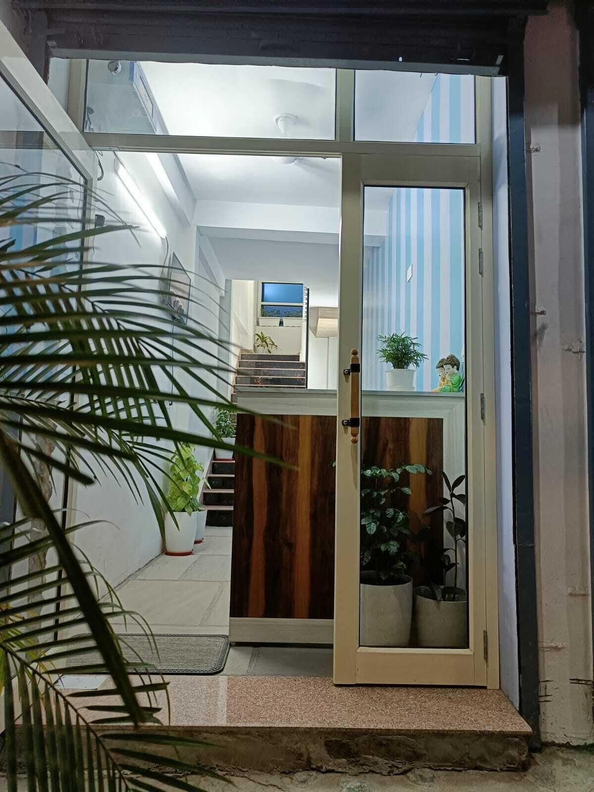 A doorway leading to a room with a wooden cabinet, a television, and potted plants.