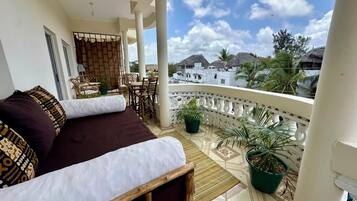 A balcony with a sofa, chairs, and potted plants.