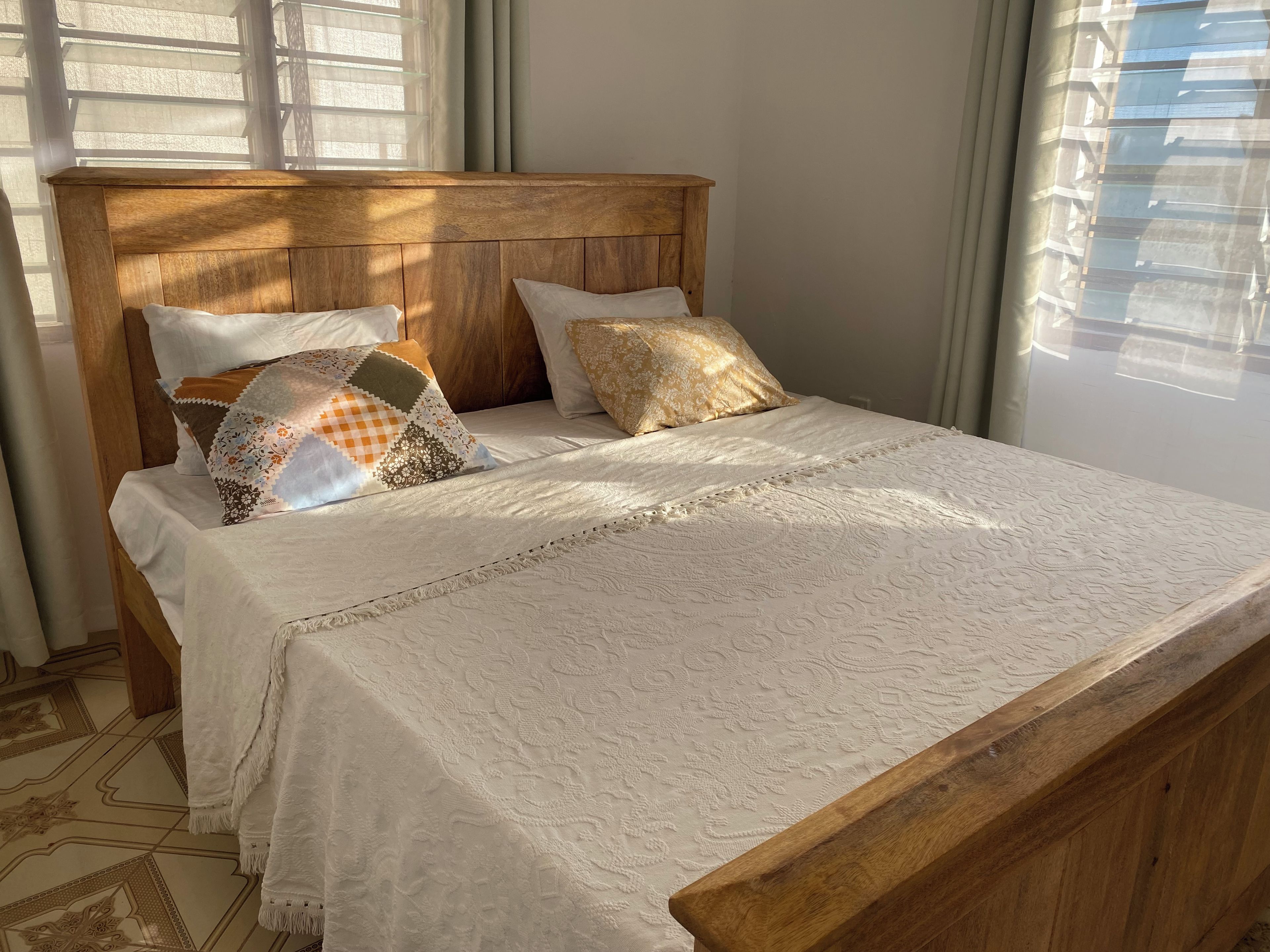 A bed with a wooden headboard, white bedding, and patterned pillows.