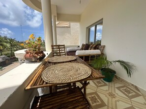 A balcony with a table and chairs, a potted plant, and a view of the sky. - Watamu city comfort apartment, with sea view from rooftop, atm , gym nearby (Watamu)