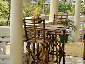 A wooden outdoor seating area with a table and chairs, surrounded by white pillars and potted plants. - Watamu city comfort apartment, with sea view from rooftop, atm , gym nearby (Watamu)