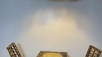A room with a woven bamboo table and chairs, a hanging light fixture, and a water dispenser.