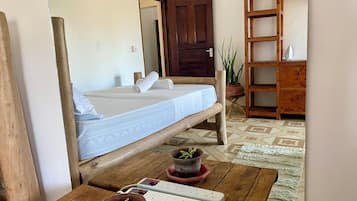 A room with a bed, wooden furniture, a power strip, and potted plants.