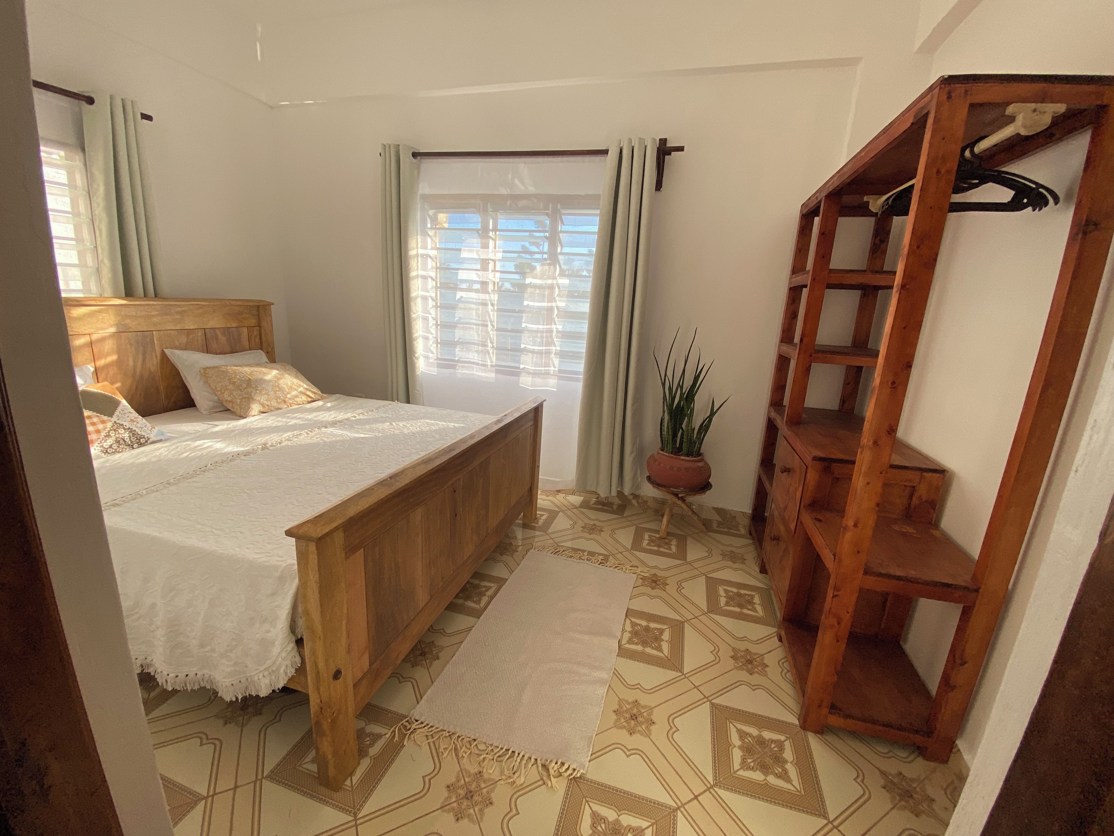Ein Schlafzimmer mit einem hölzernen Bett, einem Blumentopf und einer Holzregaleinrichtung.