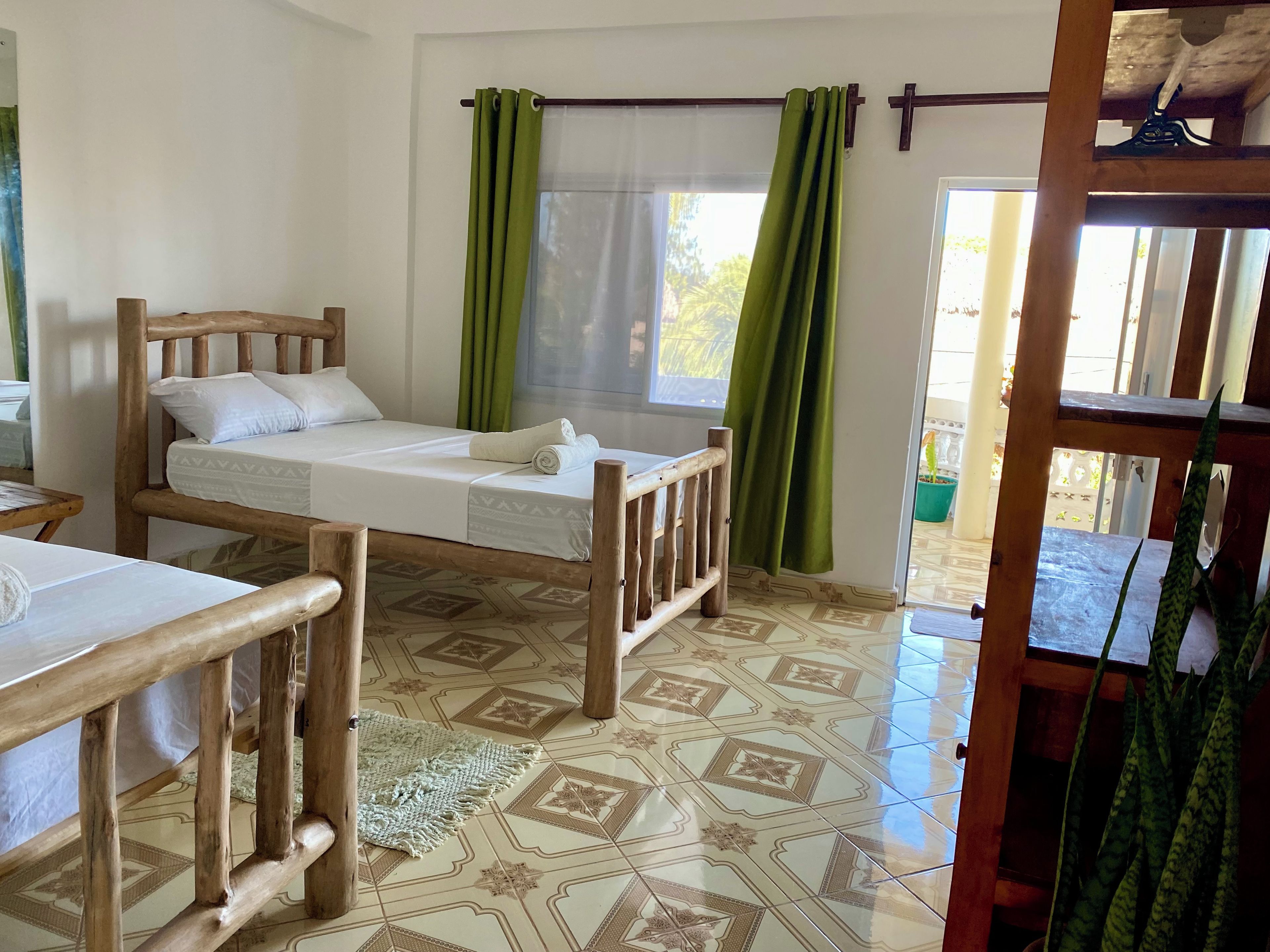 A room with a bed, a small table, and a window with curtains.
