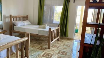 A room with a bed, a small table, and a window with curtains.